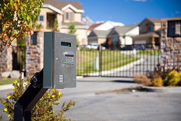 The call box outside the gate of a prestigious gated housing community. The gate and houses can be seen in the out of focus background.